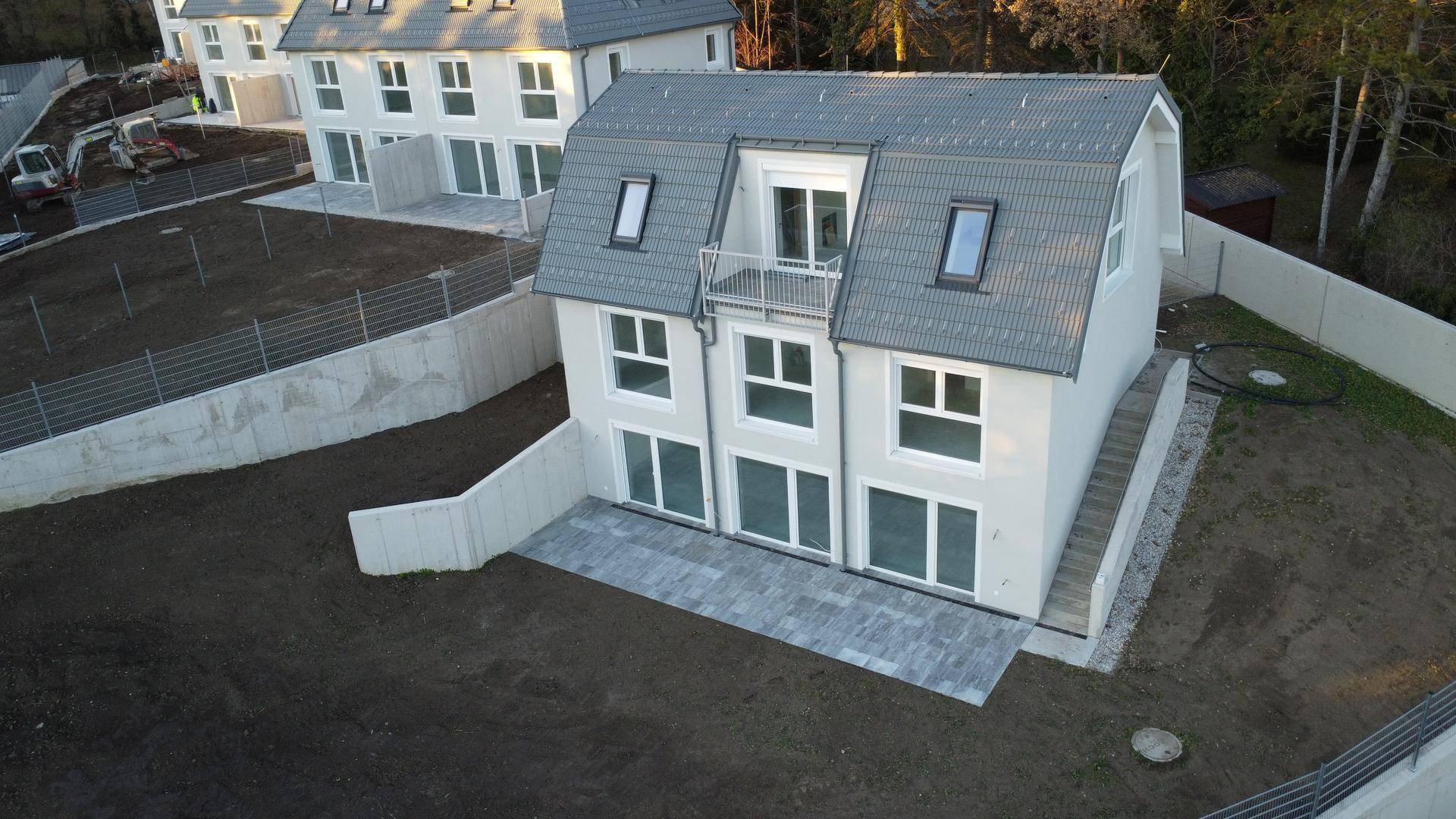 Modernes Neubauhaus mit gepflasterter Terrasse und noch unfertigem Gartenbereich, bereit zur Gestaltung.