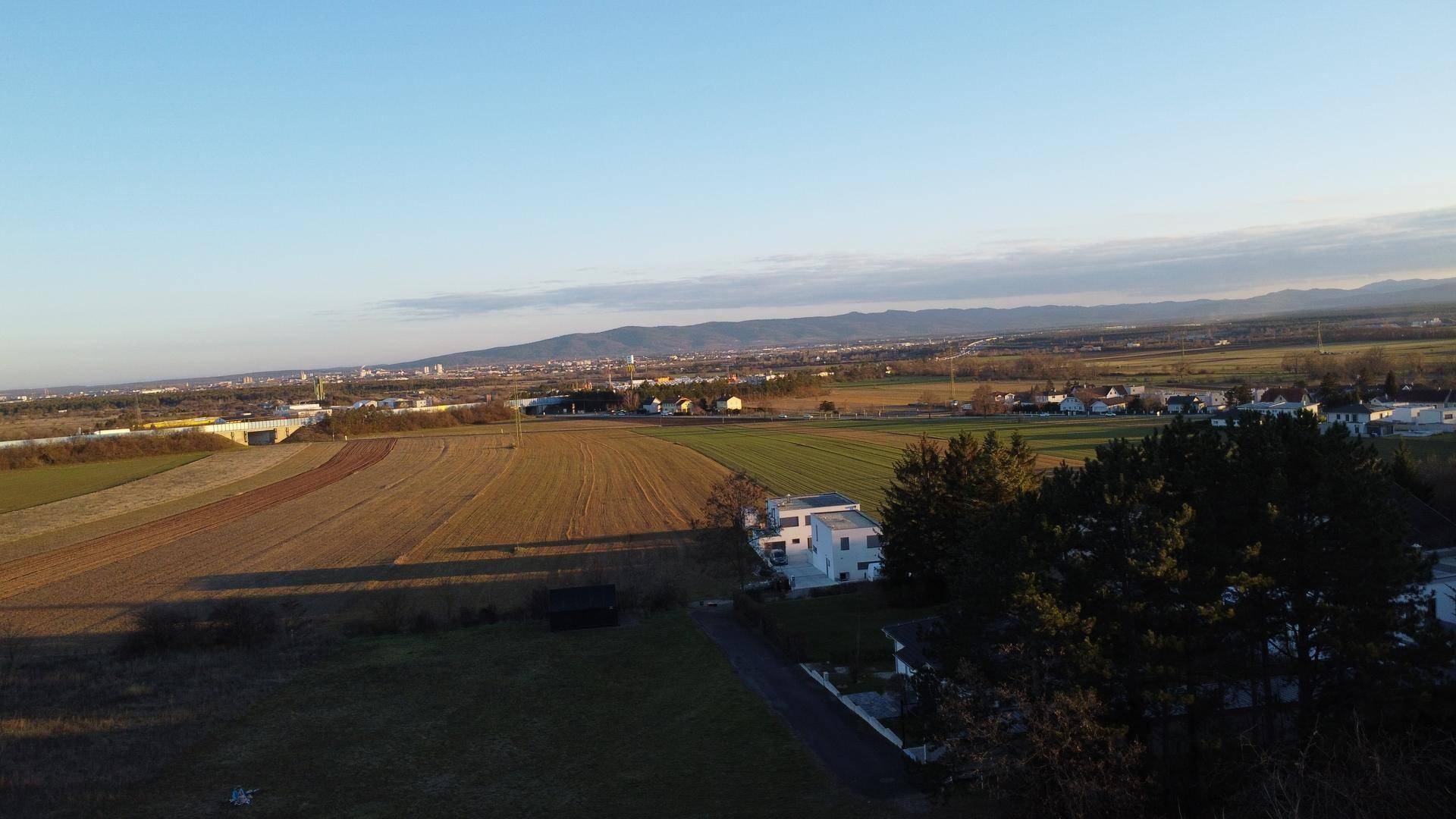 Weitläufige Luftaufnahme einer ländlichen Gegend mit Feldern, Bäumen und einer Stadt in der Ferne.