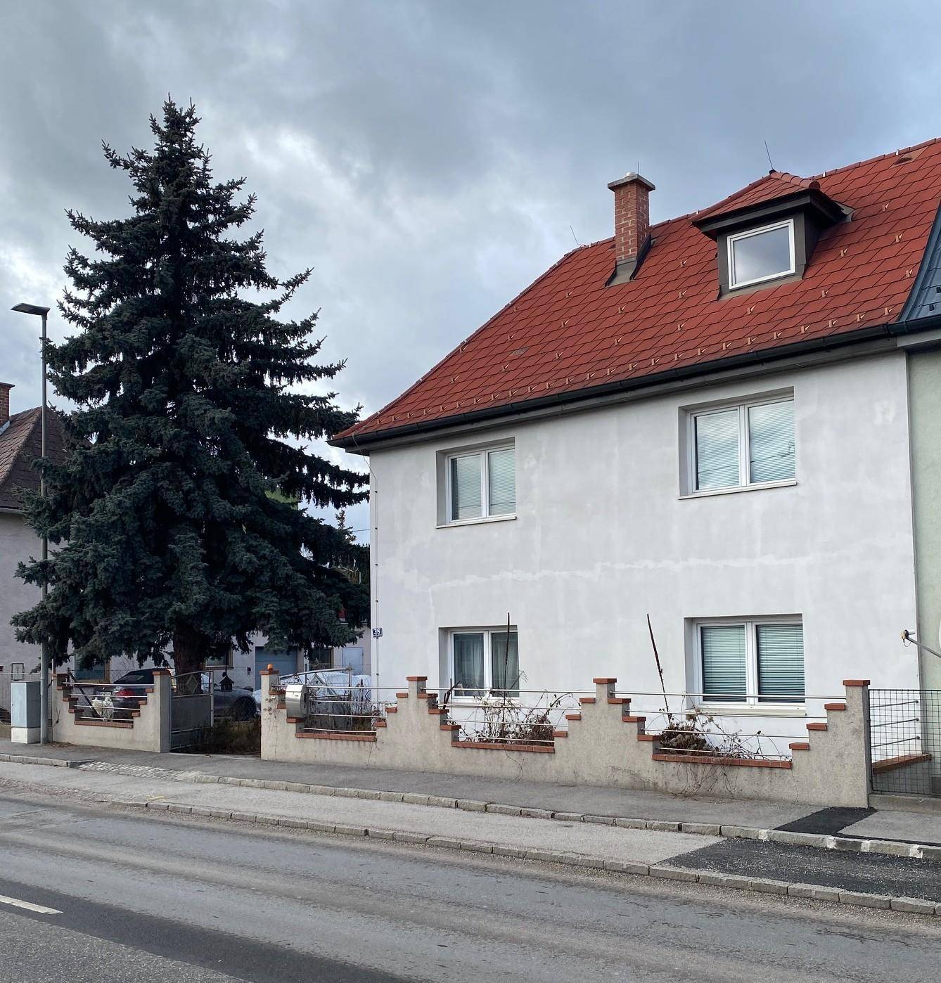 Seitenansicht des Wohnhauses mit rotem Ziegeldach und Vorgartenbereich.