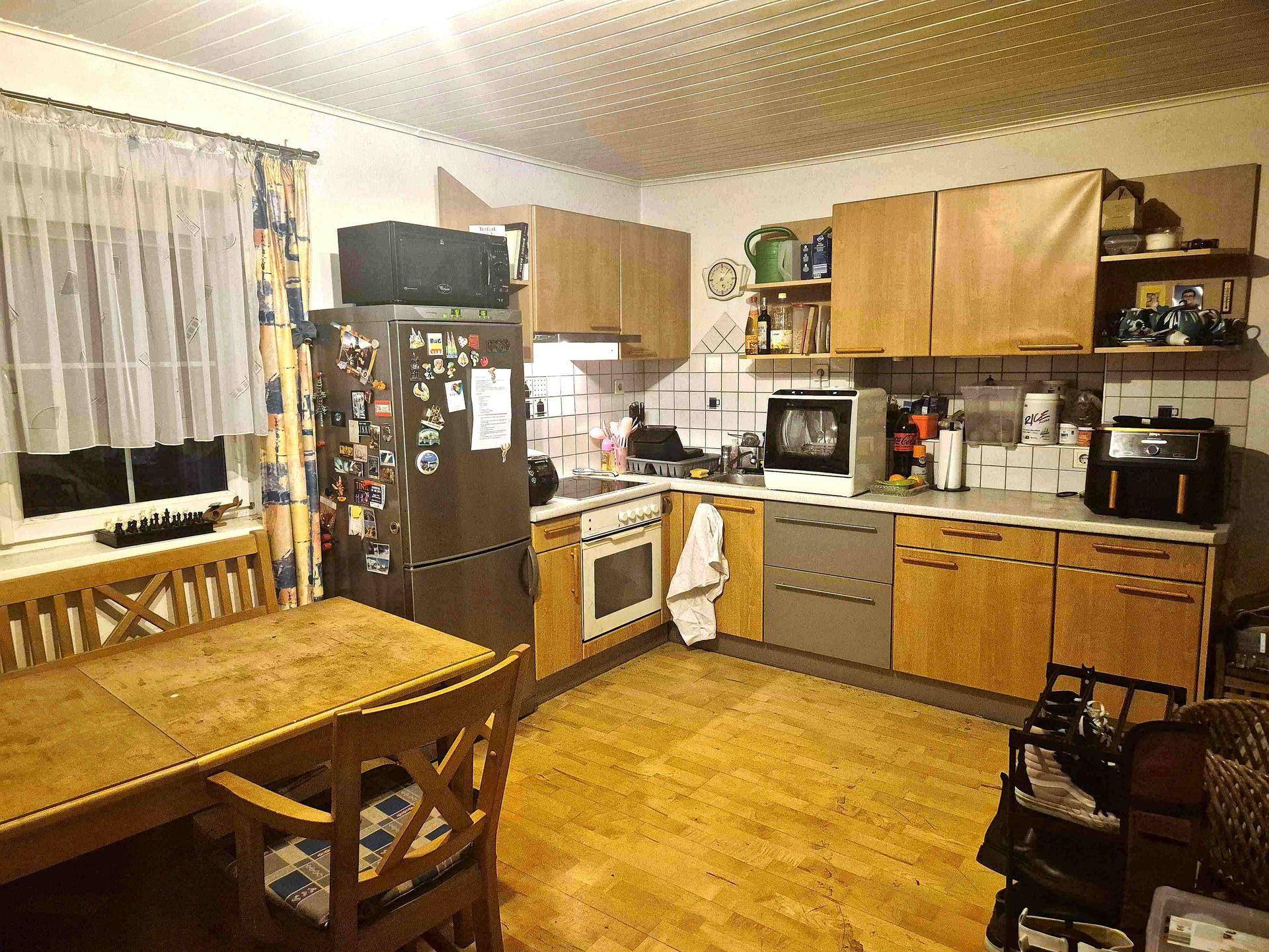 Gemütliche Küche mit Holzboden, Einbauküche und Essbereich am Fenster.