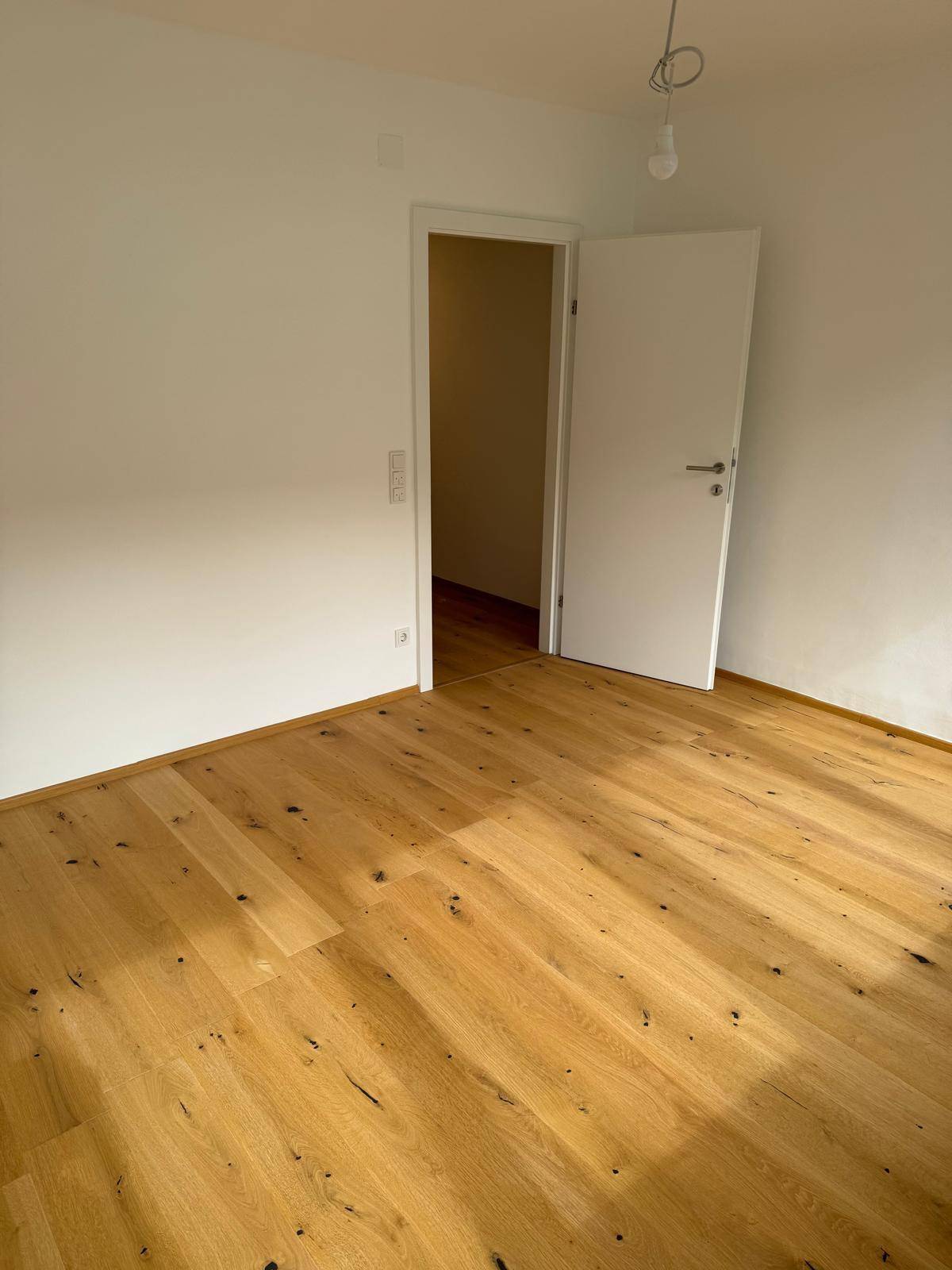 Geräumiges Zimmer mit Eichenparkett und weiß gestrichenen Wänden, bereit zum Einzug.