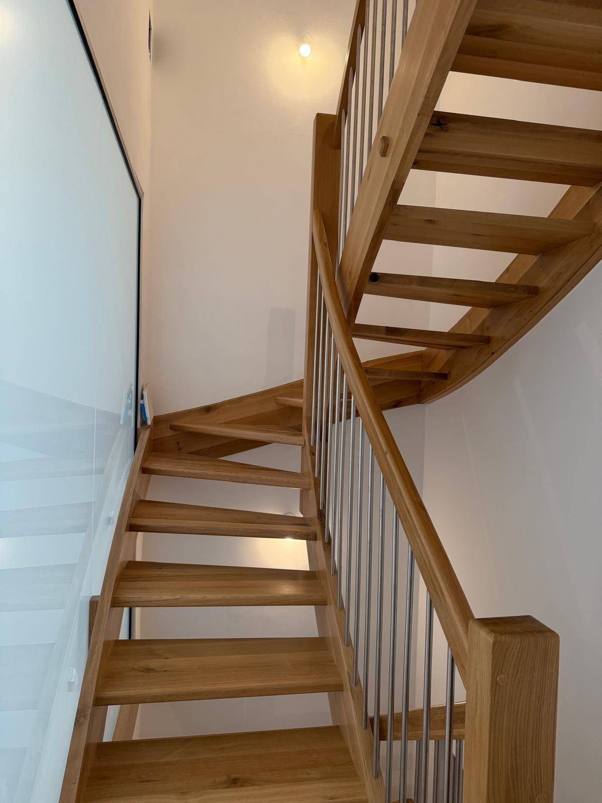 Moderne Holztreppe mit Metallgeländer, die die verschiedenen Ebenen verbindet.