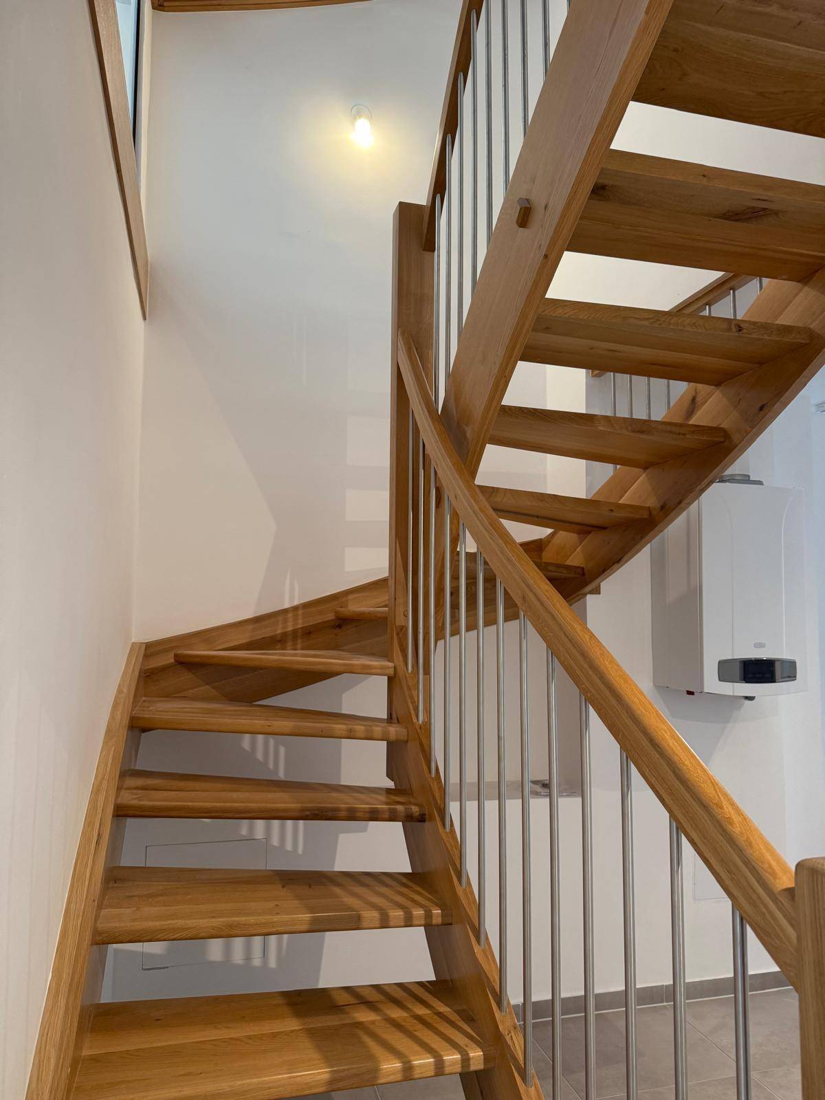 Elegante Holztreppe mit Metallstäben und einem Heizkessel im Hintergrund.