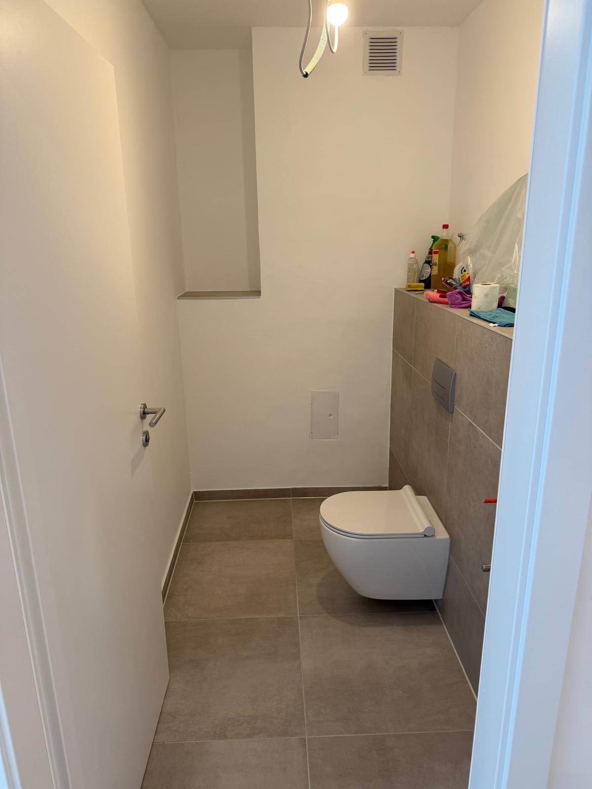 Kleines Gäste-WC mit Wand-WC und modernen grauen Fliesen.