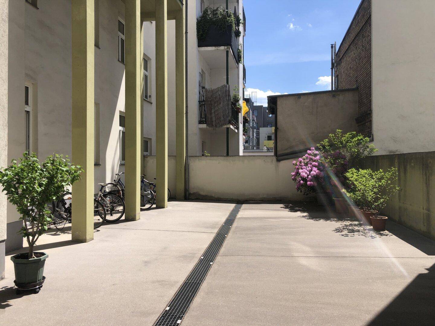 Innenhof mit Betonfläche, Topfpflanzen und Fahrradabstellmöglichkeiten, bietet praktischen Raum.
