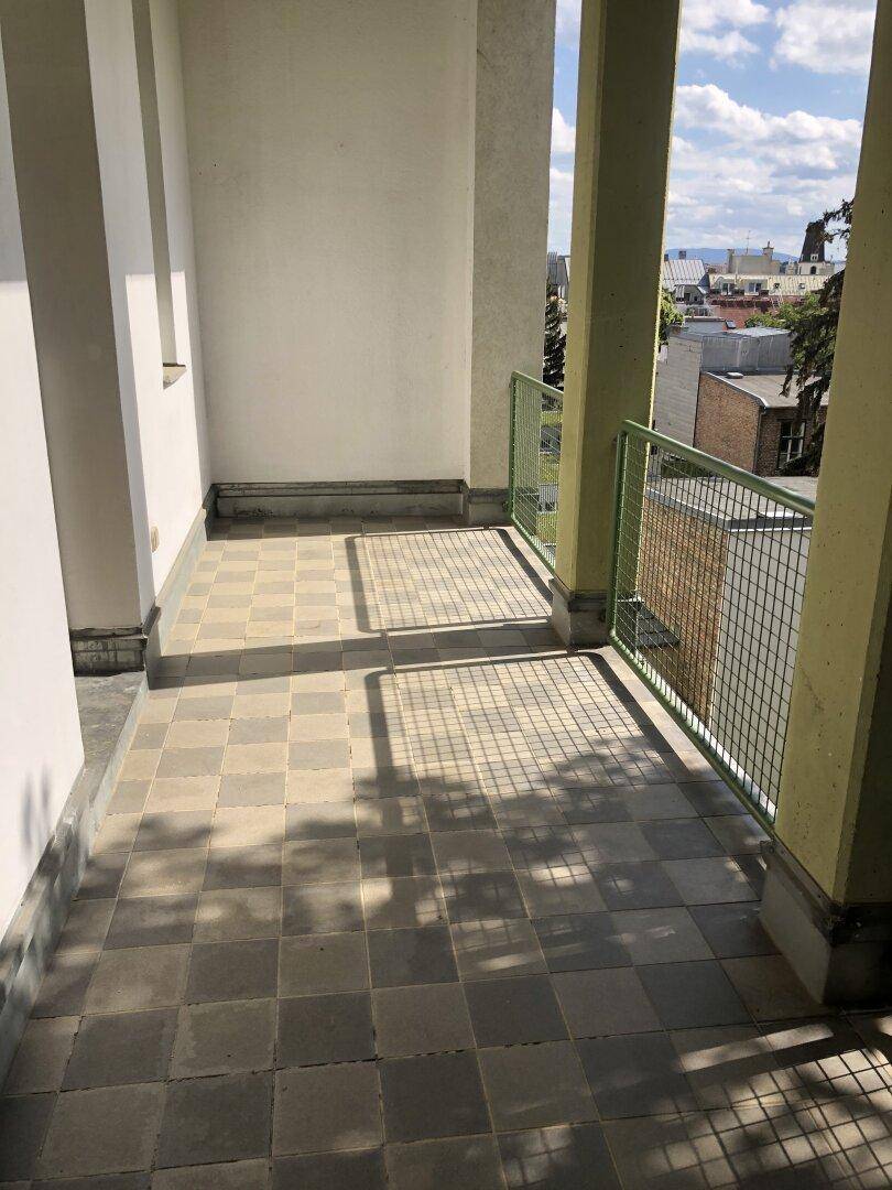 Geräumiger Balkon mit Fliesenboden und weitem Blick über die Dächer der Stadt.