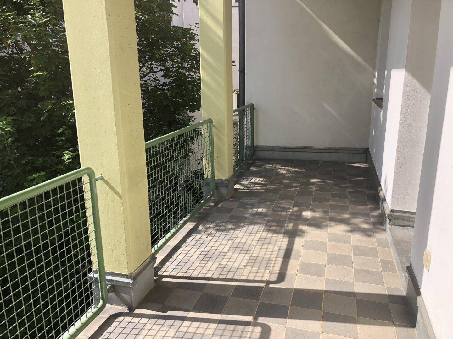 Sonniger Balkon mit karierten Fliesen und Gittergeländer, ideal für entspannte Stunden im Freien.