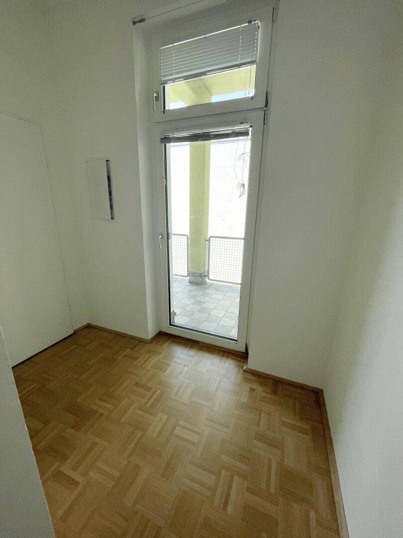 Kleines Zimmer mit Parkettboden und direktem Zugang zum Balkon durch eine Glastür.
