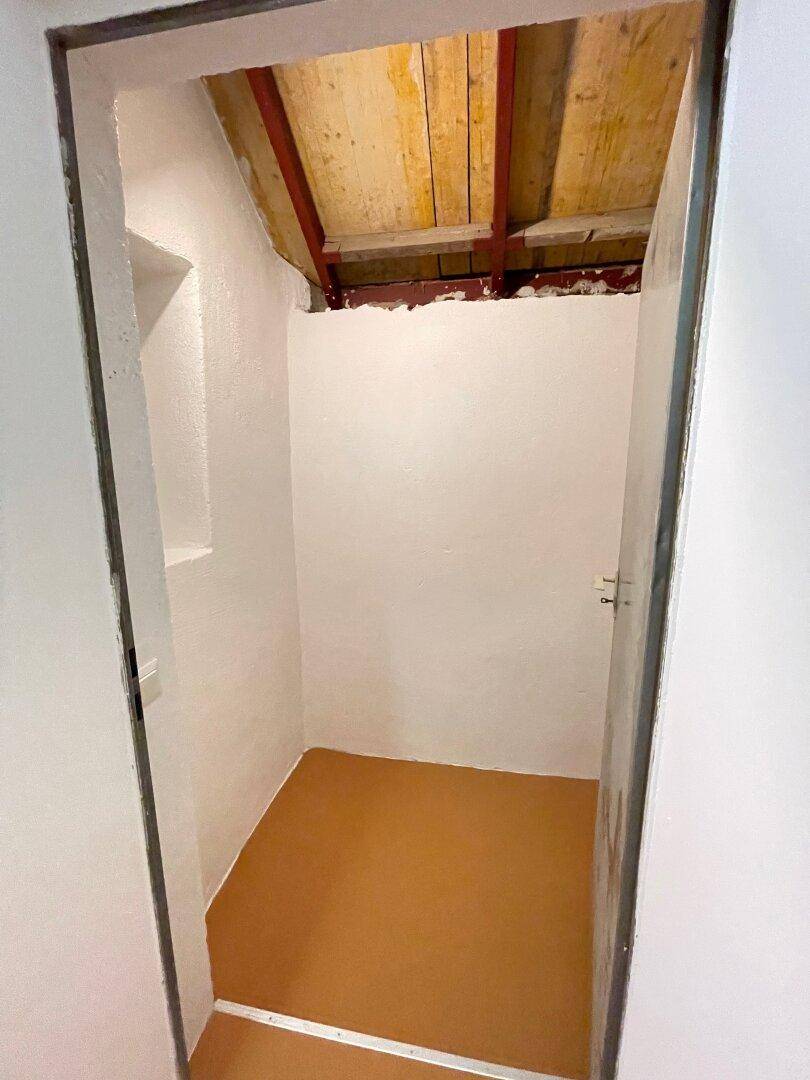 Kleiner Abstellraum mit schrägen Wänden und Holzdachkonstruktion, ideal für Lagerung.