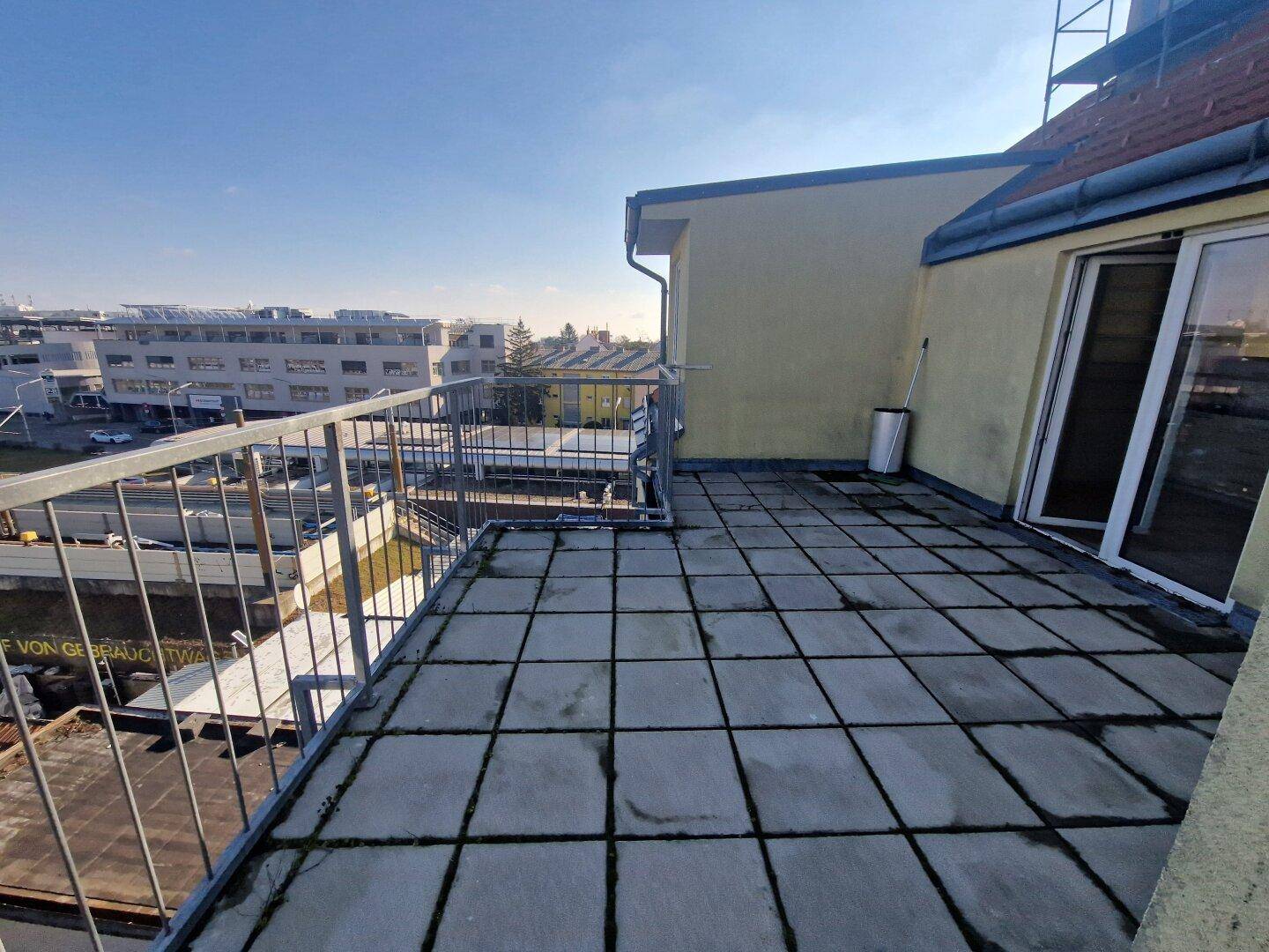 Geräumige Dachterrasse mit Fliesenboden und Metallgeländer, bietet einen weiten Blick über die Umgebung.