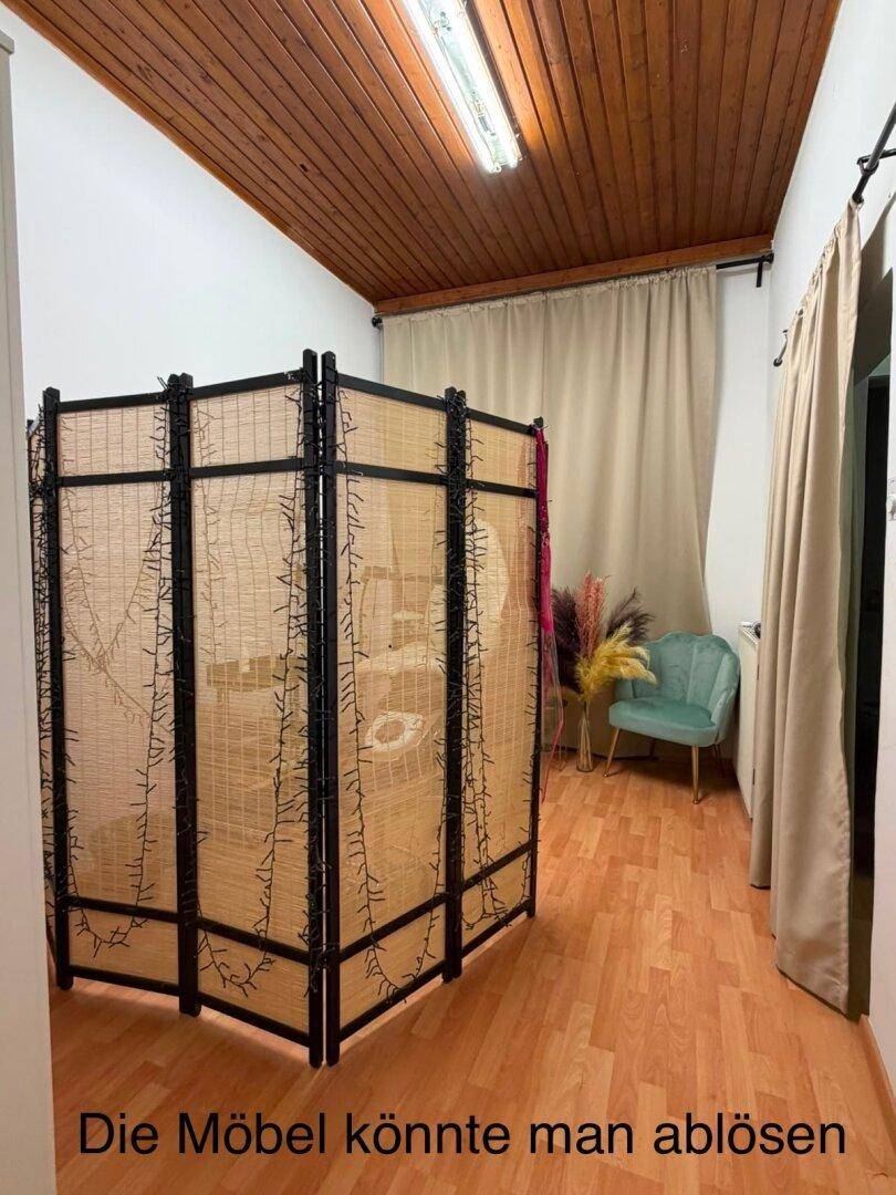 Raum mit Holzdecke, Laminatboden und einem dekorativen Paravent mit Lichterkette.