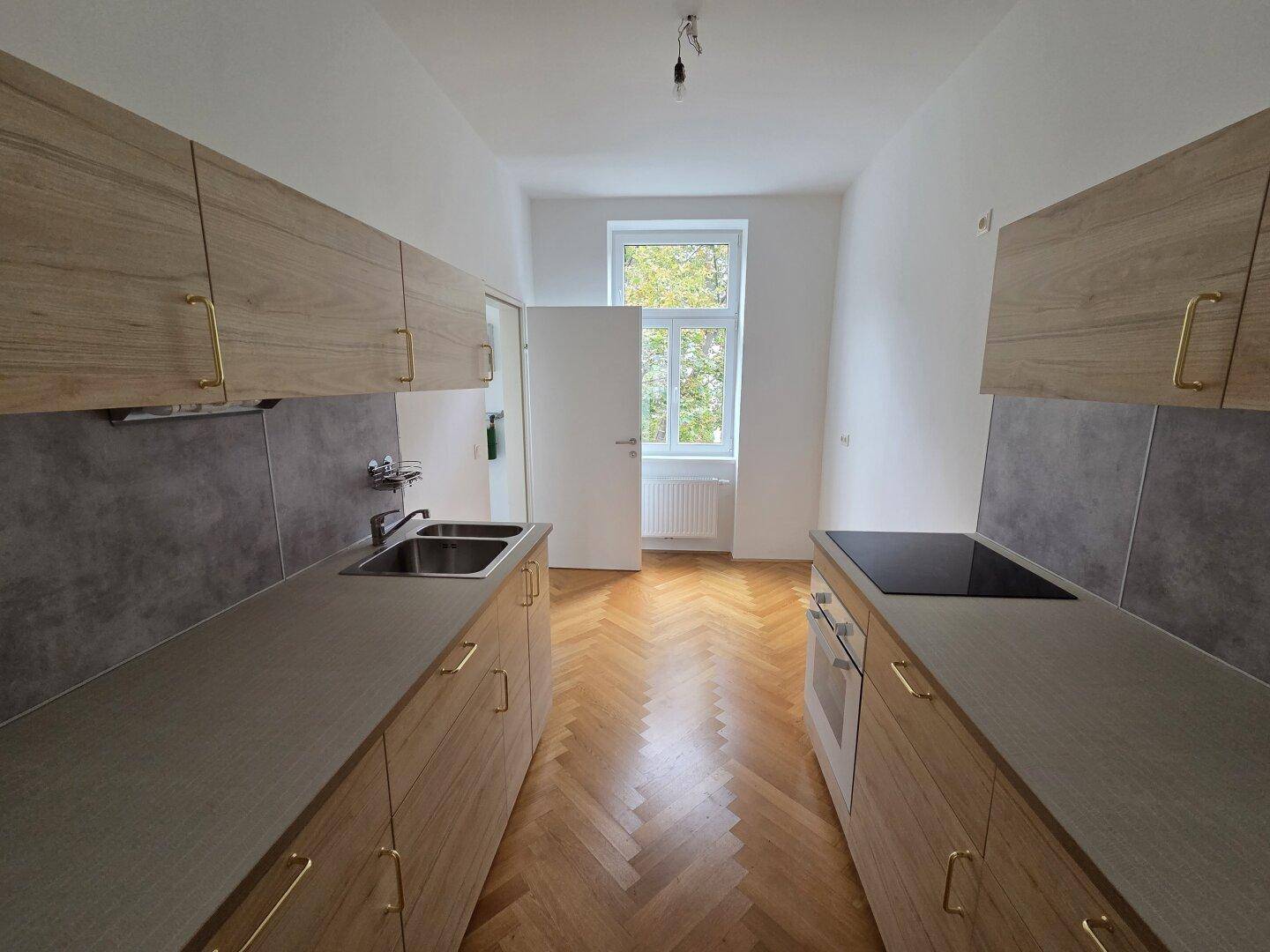 Neue Küche mit Holzoptik-Schränken, integriertem Kochfeld und Spüle, bereit zur Nutzung.