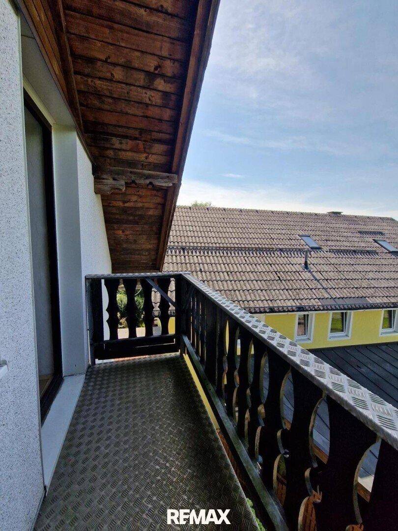 Balkon mit Holzgeländer und Blick auf die umliegenden Dächer und Gebäude.