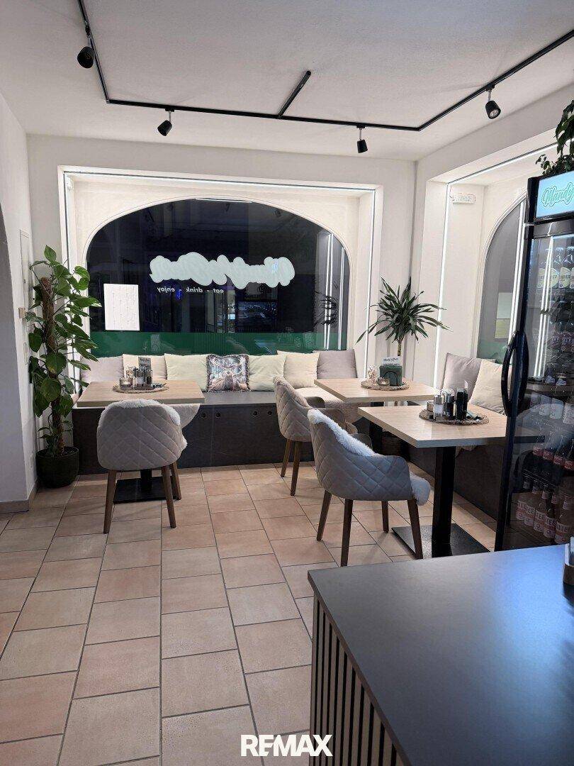 Gemütlicher Essbereich eines Diners mit Tischen, Stühlen und einer langen Sitzbank vor großen, gewölbten Fenstern.
