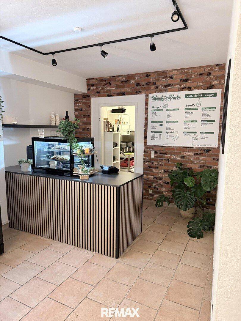 Thekenbereich eines Diners mit einer Holzlamellenverkleidung, einer Ziegelwand und einer Menütafel.