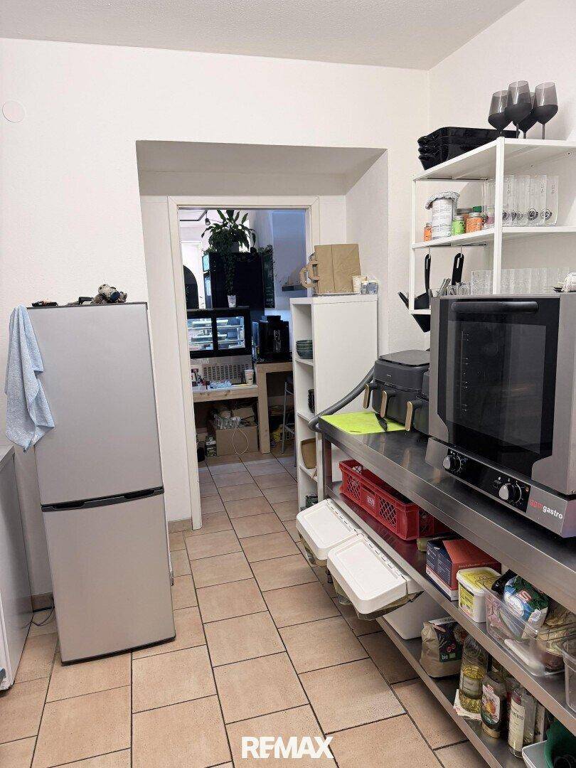Gewerbliche Küche mit Edelstahlregalen, einem Ofen und einem Kühlschrank, bereit für den Restaurantbetrieb.
