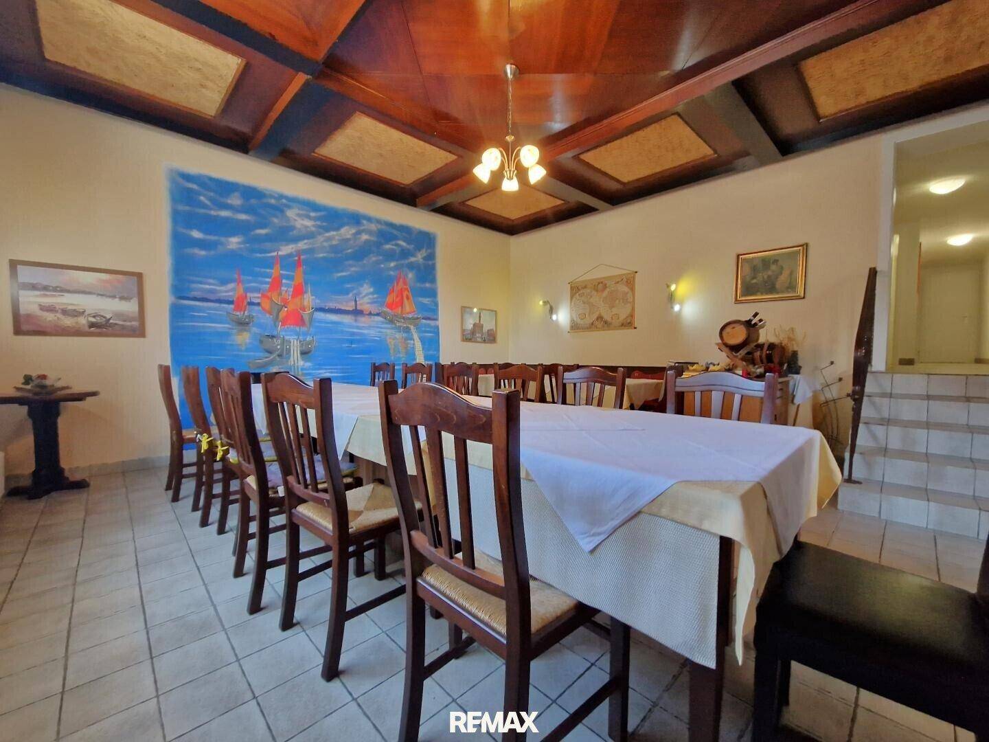Großer Speisesaal mit langer Tafel, Holzkassettendecke und einem auffälligen Wandgemälde.
