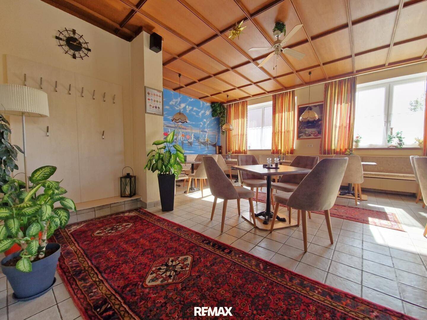 Gemütlicher Speisesaal mit Holzkassettendecke, Fliesenboden und Garderobe an der Wand.