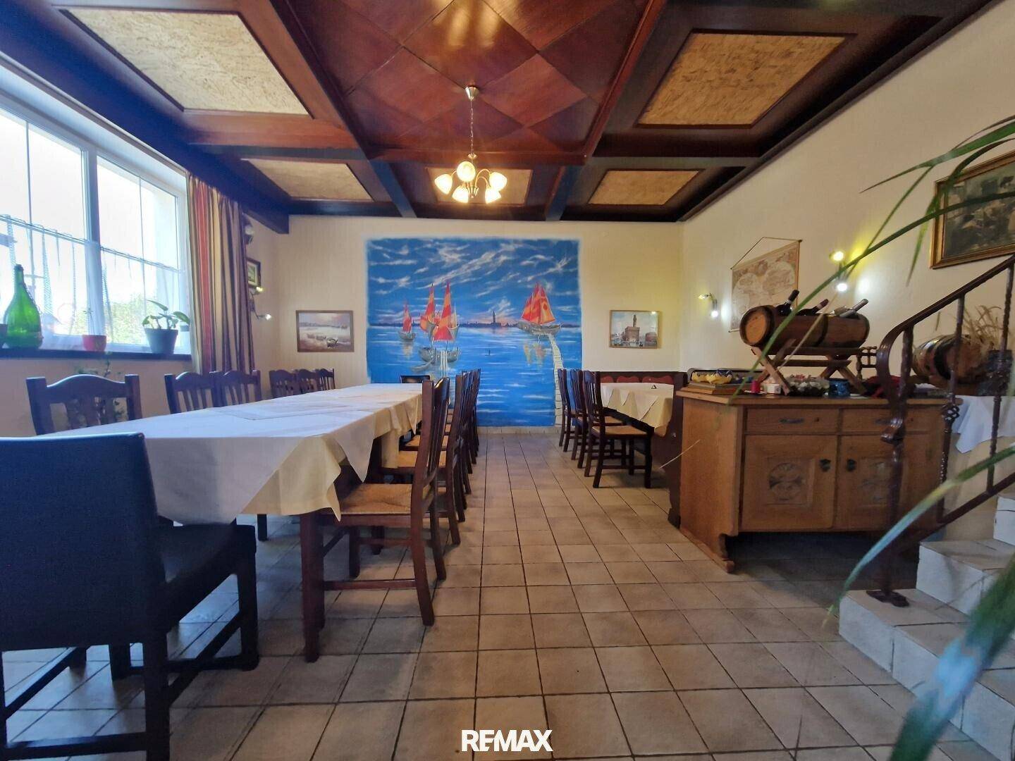 Geräumiger Speisesaal mit langer Tafel, Holzkassettendecke und traditionellem Holzschrank mit Fässern.