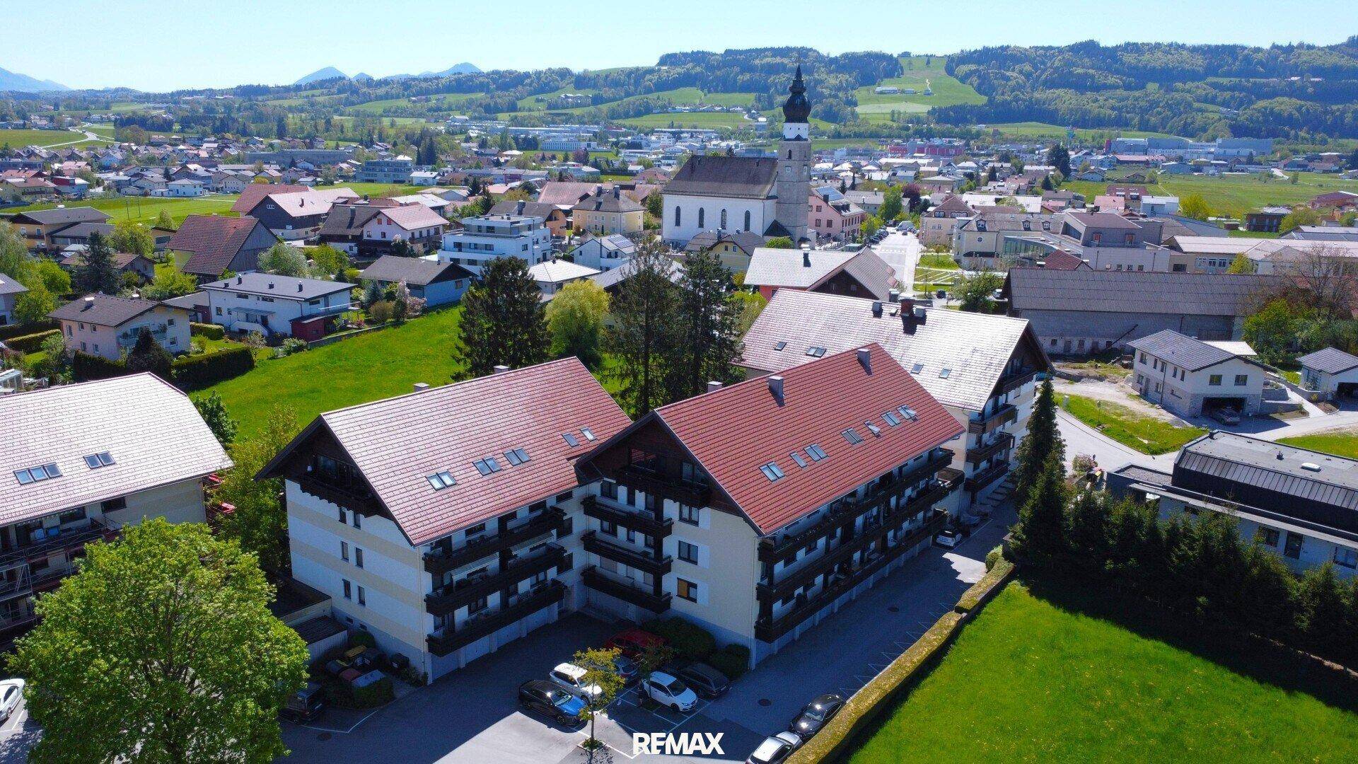 Luftaufnahme eines Wohnkomplexes mit roten Dächern und grüner Umgebung in einer ländlichen Gegend.