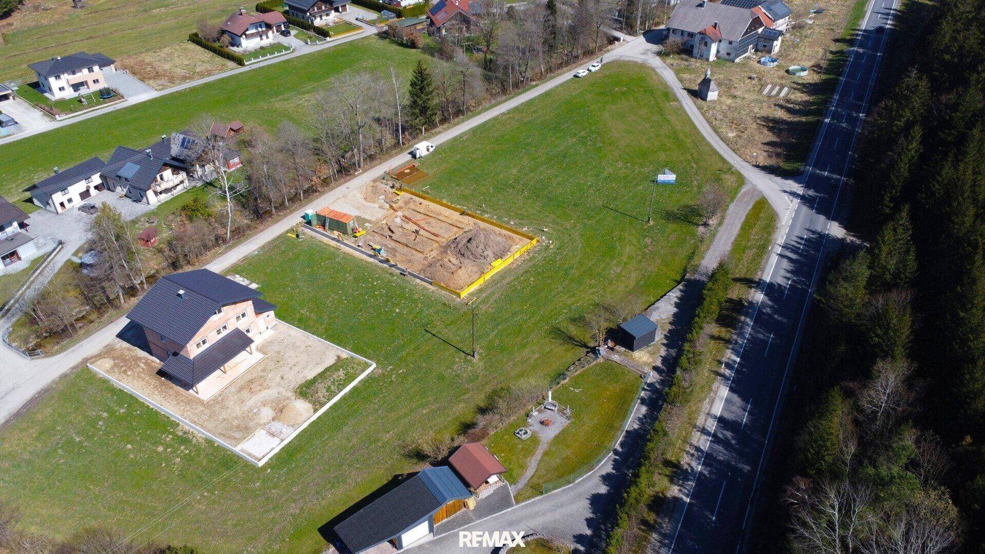 Luftaufnahme eines Neubaus mit angrenzender Baustelle in ländlicher Umgebung.