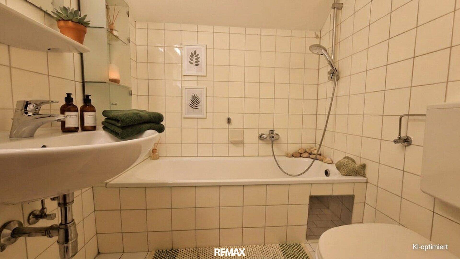 Funktionales Badezimmer mit hellbeigen Fliesen, Badewanne mit Duschfunktion und Waschbecken.