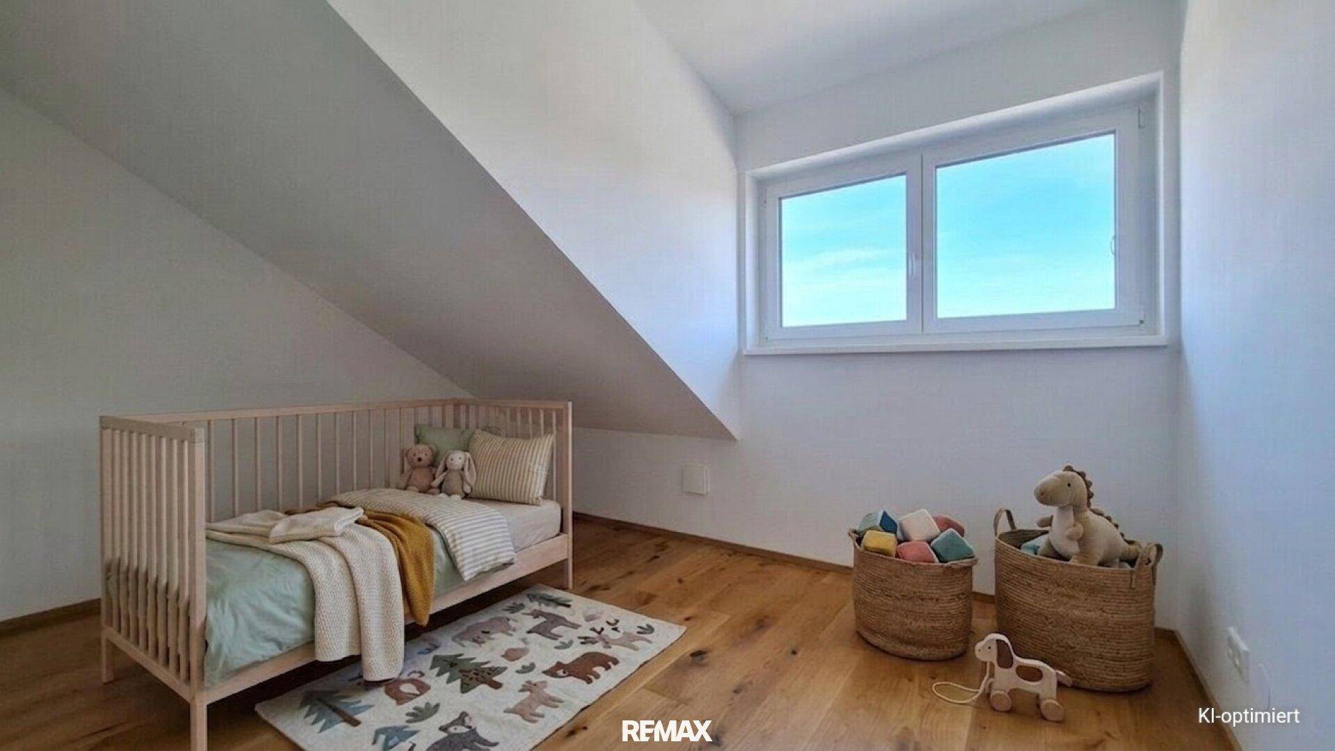 Helles Kinderzimmer im Dachgeschoss mit Holzboden und Fenster.