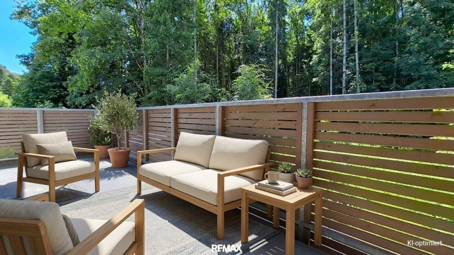Möblierte Terrasse mit Holzzaun und Blick ins Grüne.