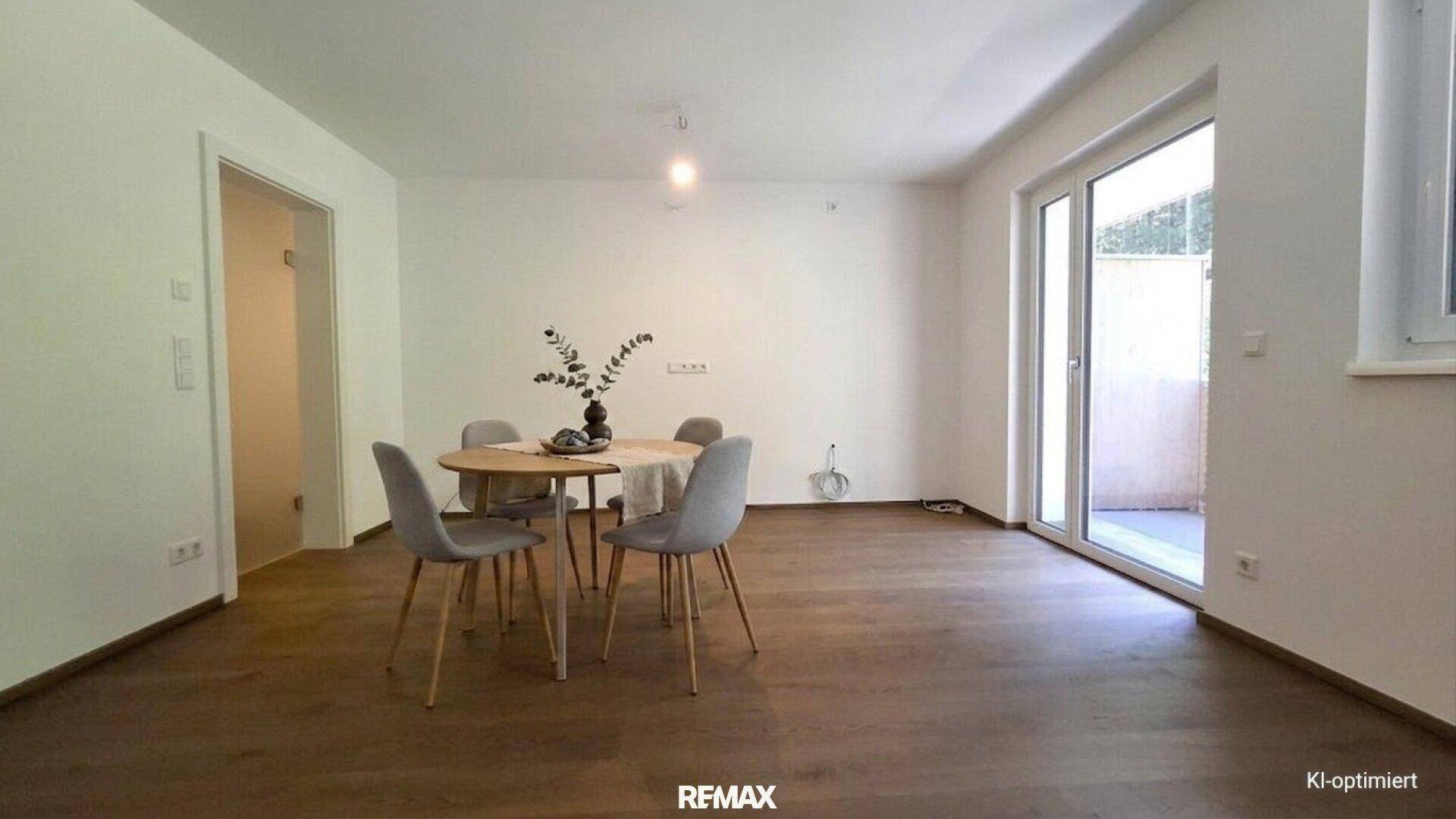 Essbereich mit Holzboden, modernem Esstisch und Zugang zu einem Außenbereich durch eine große Glastür.