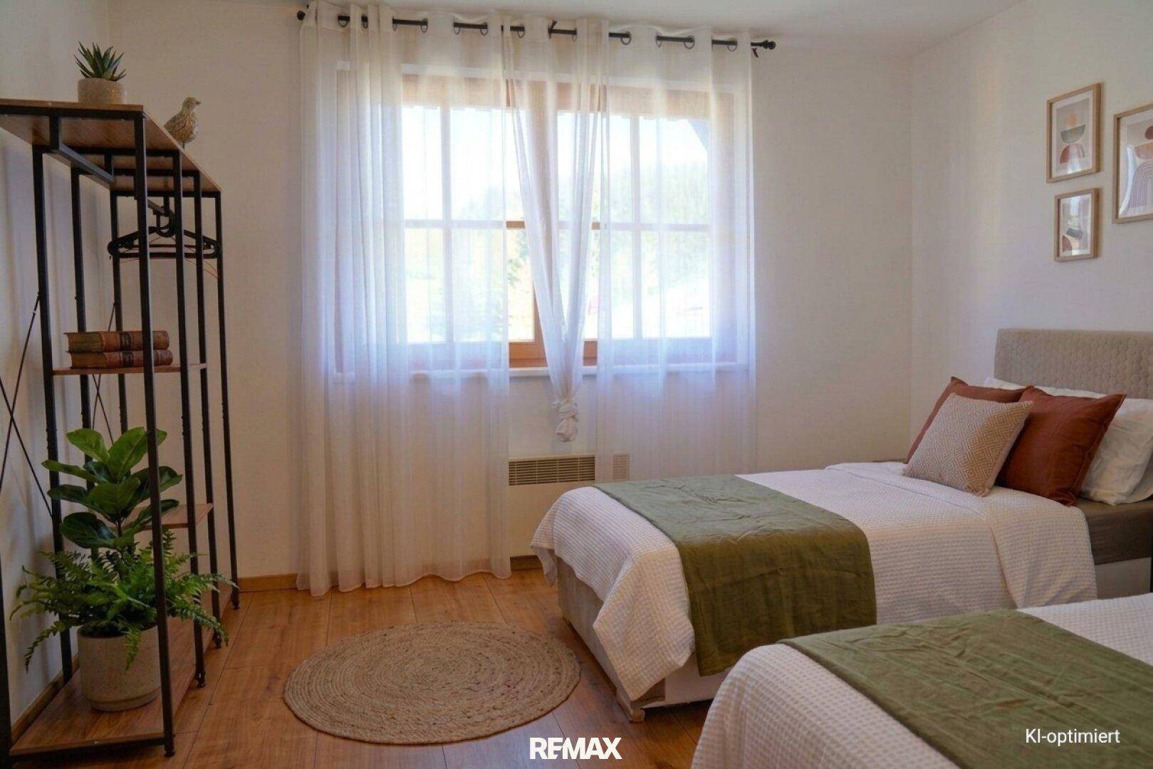 Gemütliches Schlafzimmer mit zwei Einzelbetten, Holzboden und einem großen Fenster für viel natürliches Licht.