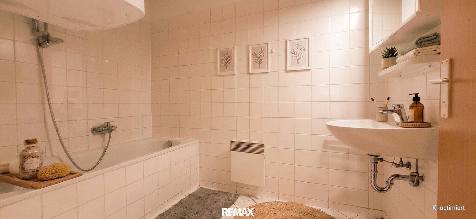 Helles Badezimmer mit weißen Fliesen, Badewanne und modernem Waschbecken, das einen gepflegten Eindruck macht.