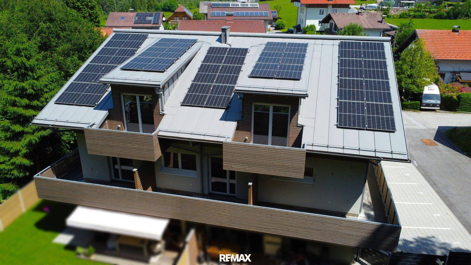 Ansicht des Wohnhauses von oben mit zahlreichen Solarmodulen auf dem Dach und modernen Balkonstrukturen.