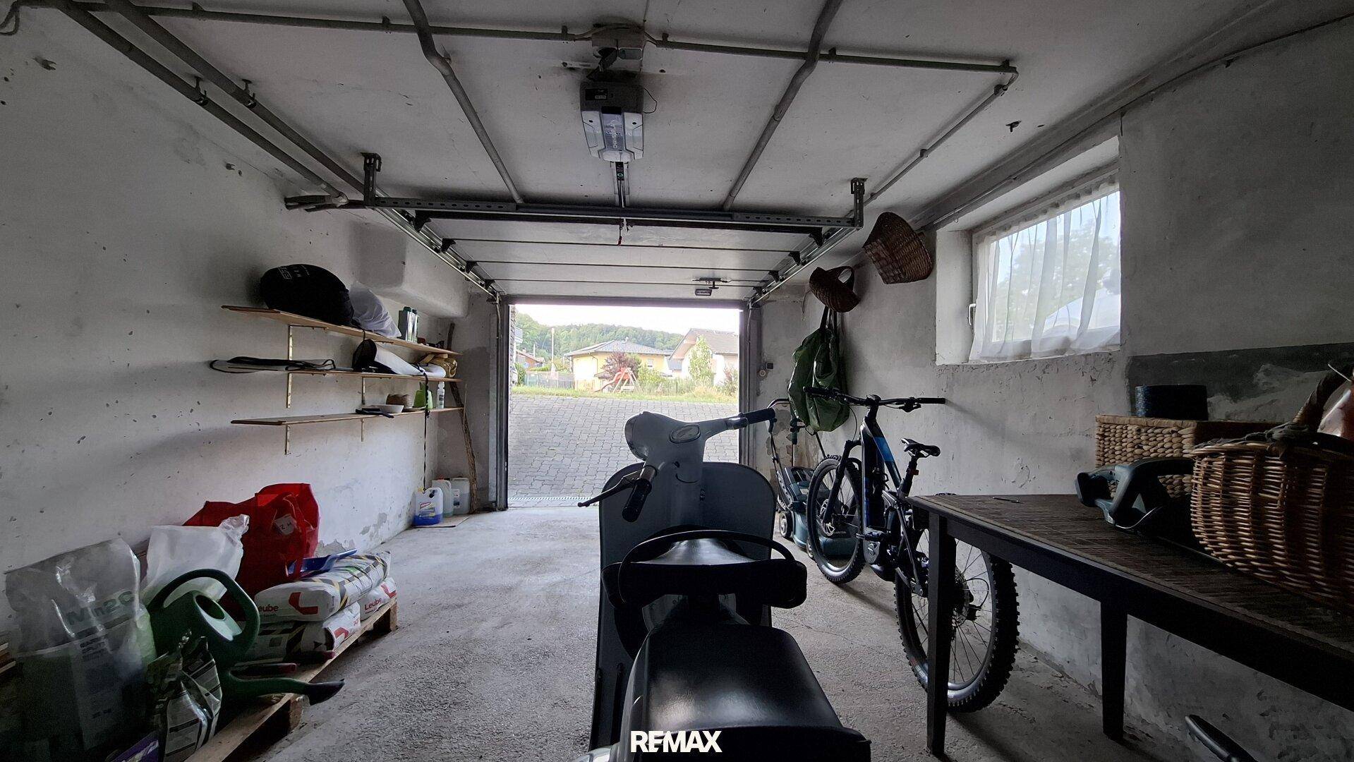 Innenansicht der Garage mit Roller, Fahrrad und verschiedenen Lagergegenständen für den täglichen Bedarf.
