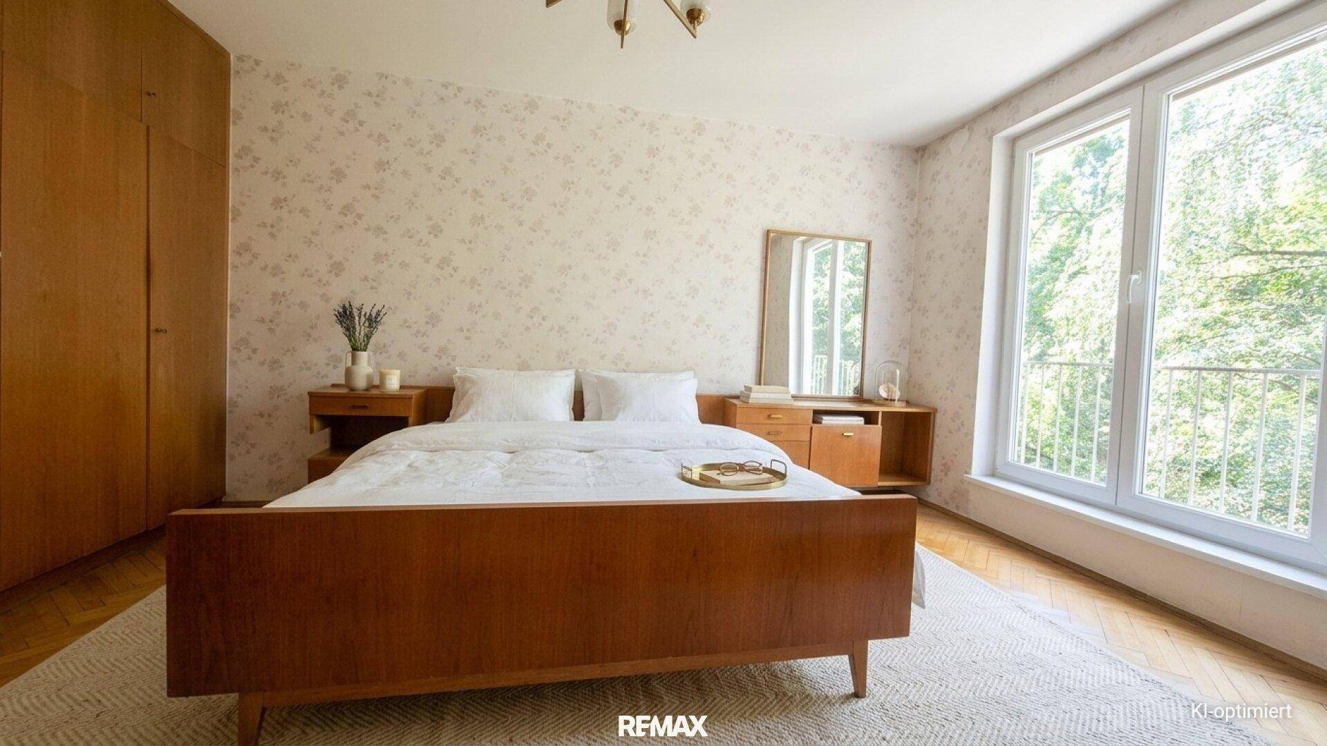 Helles Schlafzimmer mit Parkettboden, großem Kleiderschrank und Blick ins Grüne durch das Fenster.