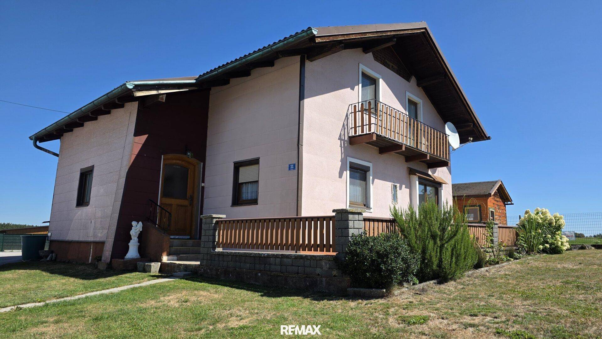 Seitenansicht des Hauses mit Balkon, Terrasse und gepflegtem Vorgarten.
