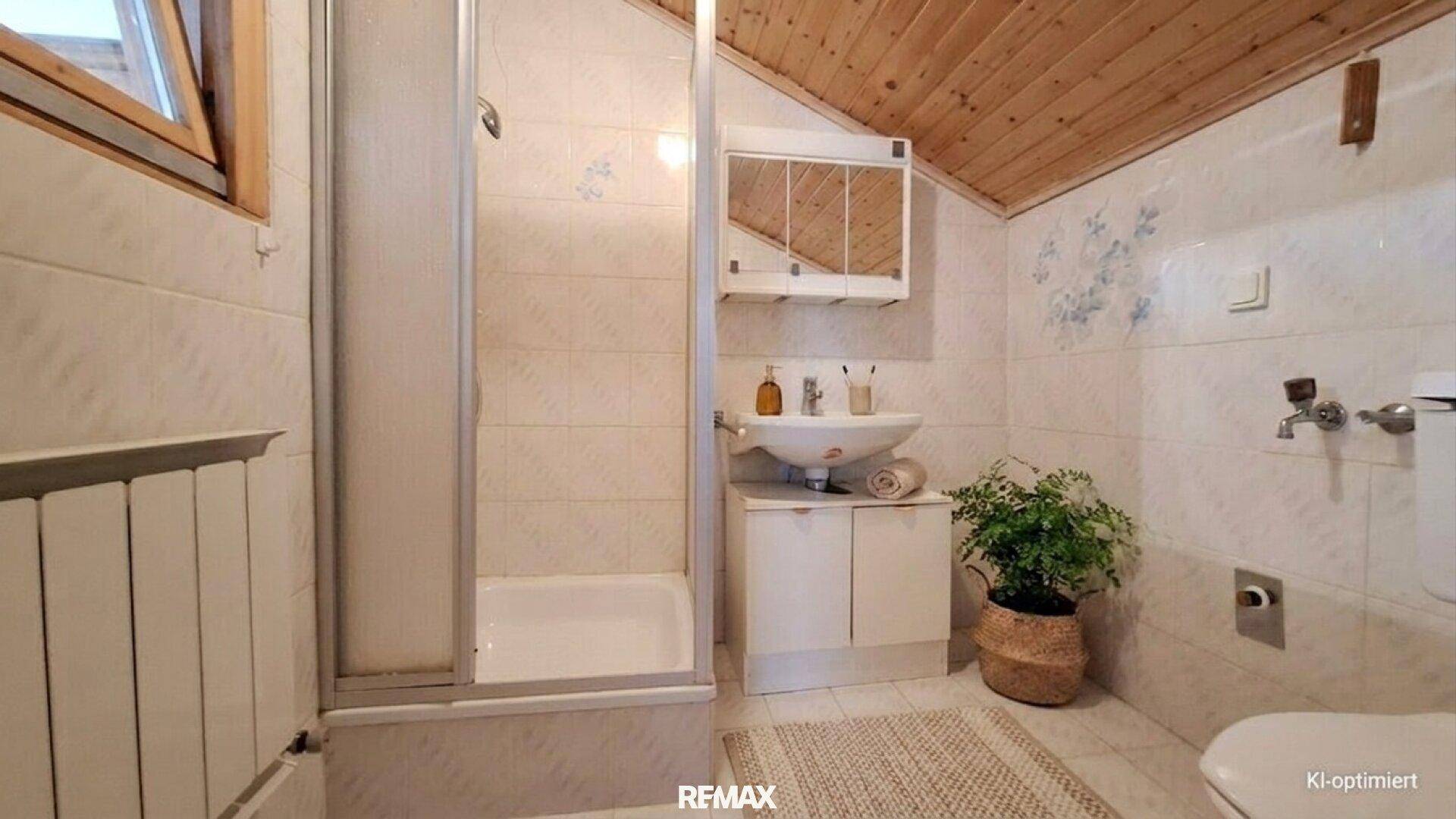 Dachgeschoss-Badezimmer mit Dusche, Waschbecken und Holzdecke.