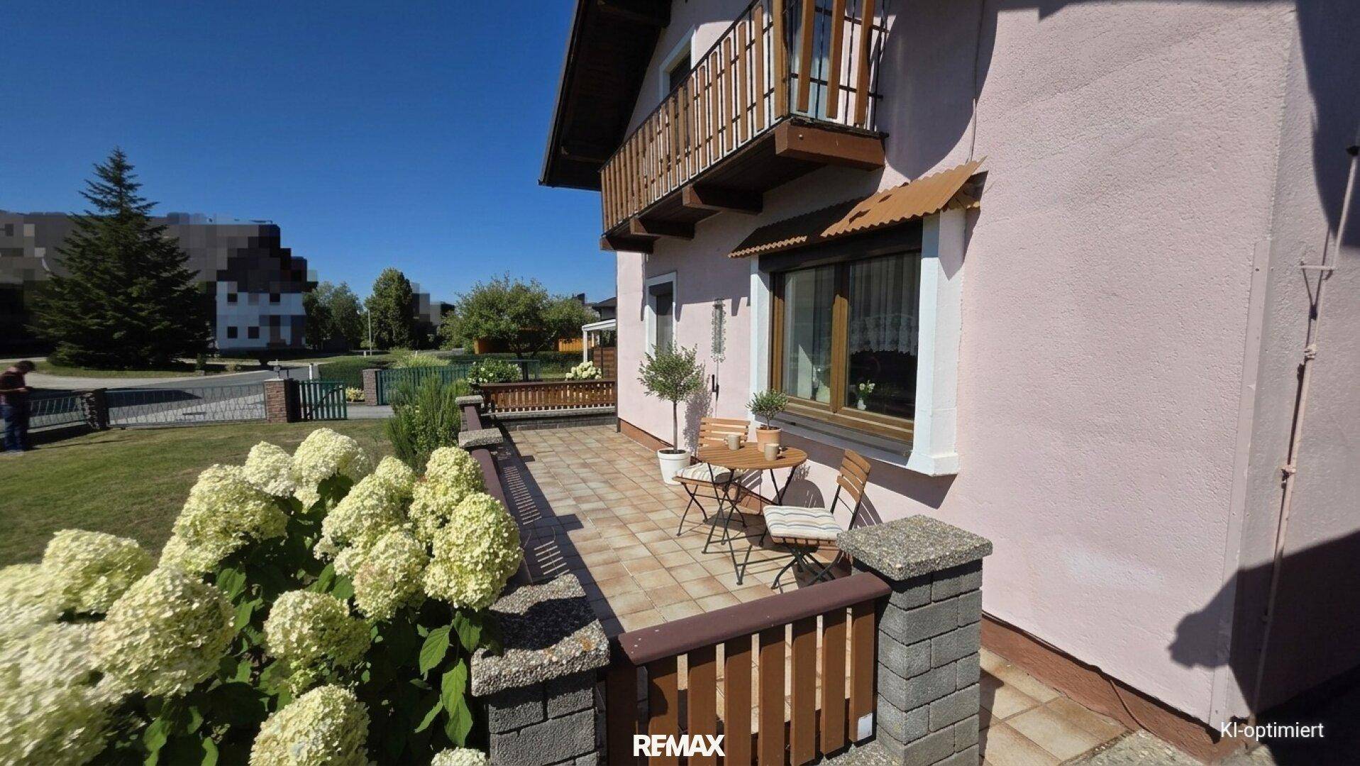 Kleine geflieste Terrasse mit Sitzgelegenheiten und Blumenbeeten.