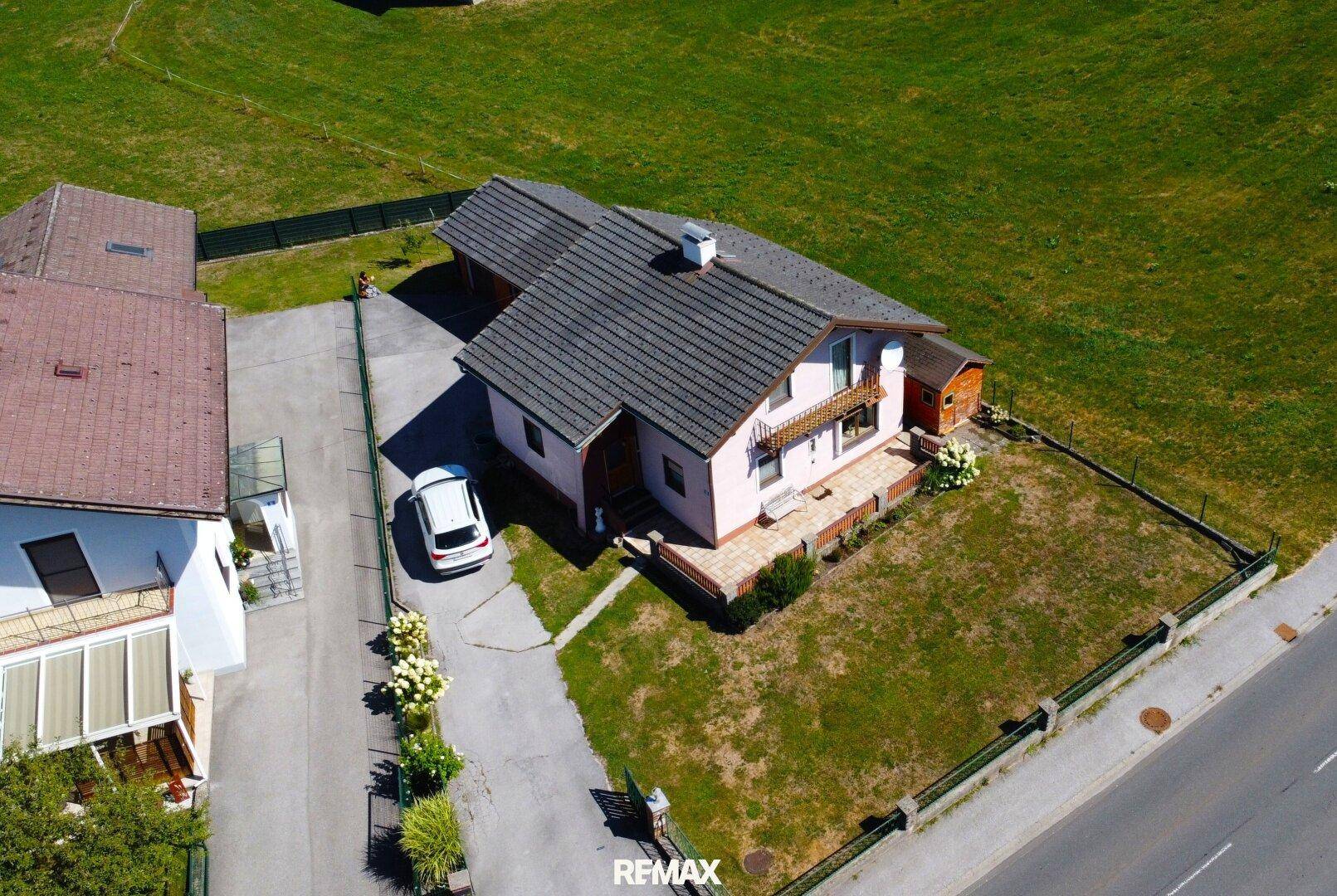 Luftaufnahme des Einfamilienhauses mit Zufahrt, Garage und großem Grundstück.