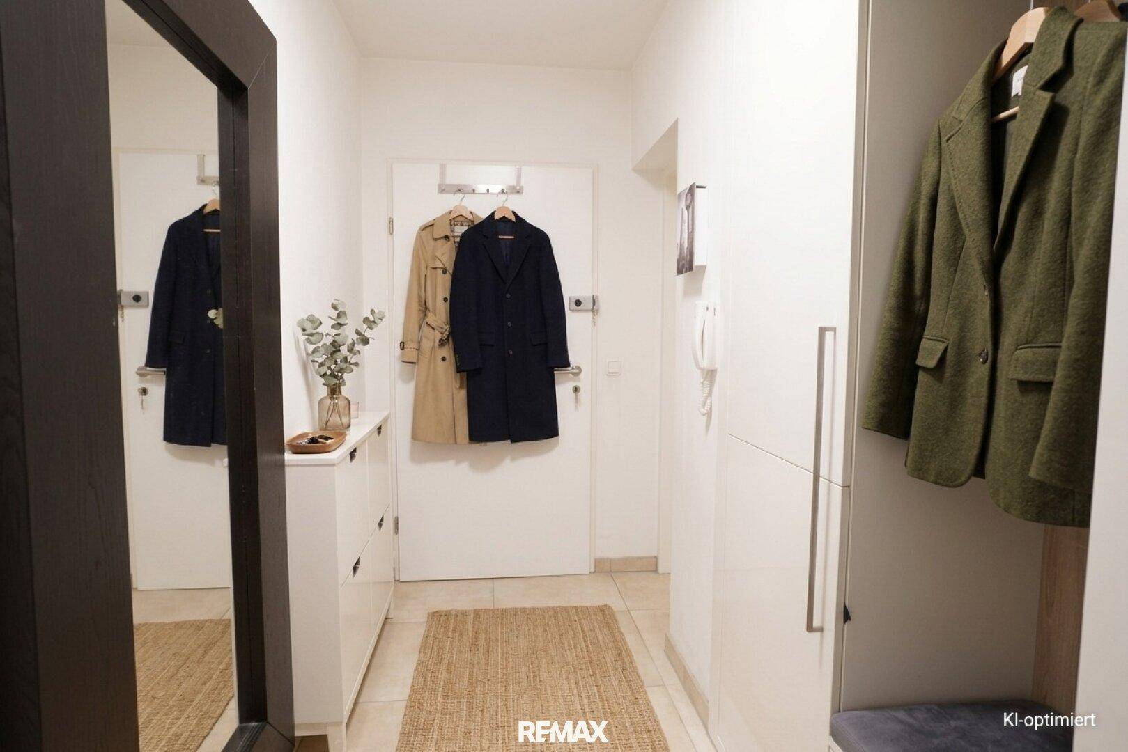 Heller Eingangsbereich mit Garderobe, Spiegel und Fliesenboden, einladend und funktional.
