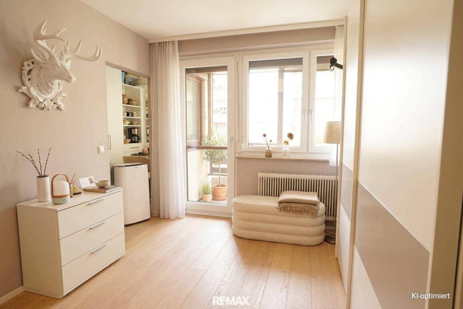 Helles Schlafzimmer mit Balkonzugang, Holzboden und moderner Einrichtung, bietet viel Tageslicht.