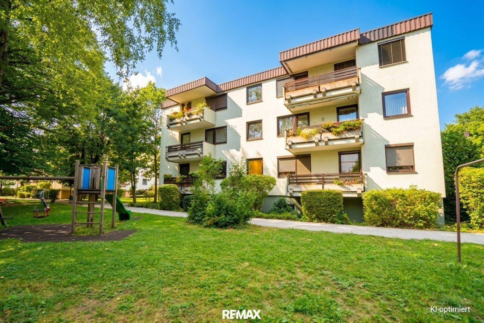 Außenansicht des Mehrfamilienhauses mit Spielplatz und gepflegter Grünfläche, ideal für Familien.
