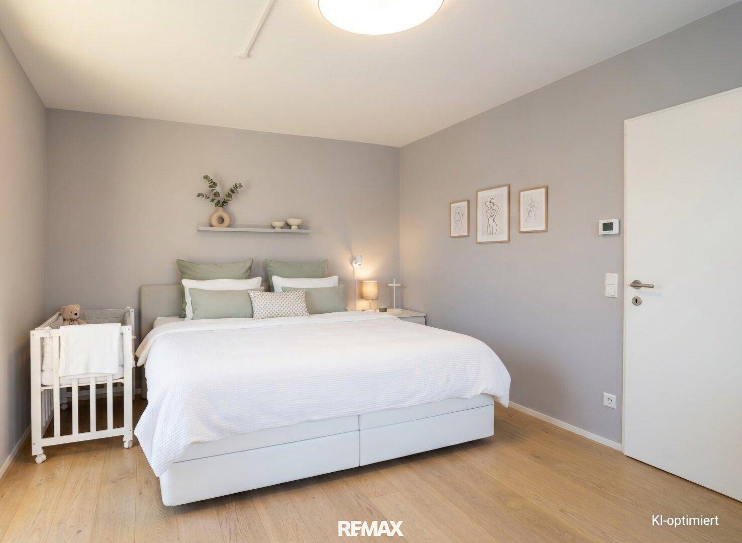 Ruhiges Schlafzimmer mit Doppelbett, hellem Holzboden und Babybett, bietet eine entspannte Atmosphäre.