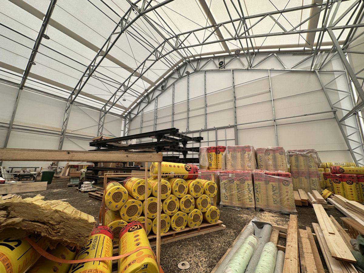 Innenansicht der Lagerhalle mit hoher Decke, sichtbaren Stahlträgern und Baumaterialien.