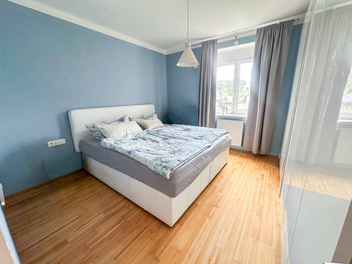 Schlafzimmer mit blau gestrichenen Wänden, Doppelbett und Holzboden.