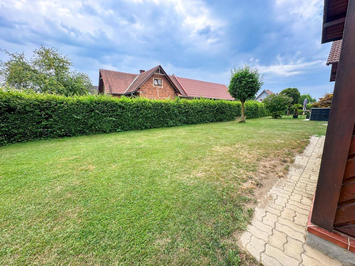 Weitläufiger Gartenbereich mit gepflegtem Rasen und hoher Hecke, ideal für Erholung im Freien.