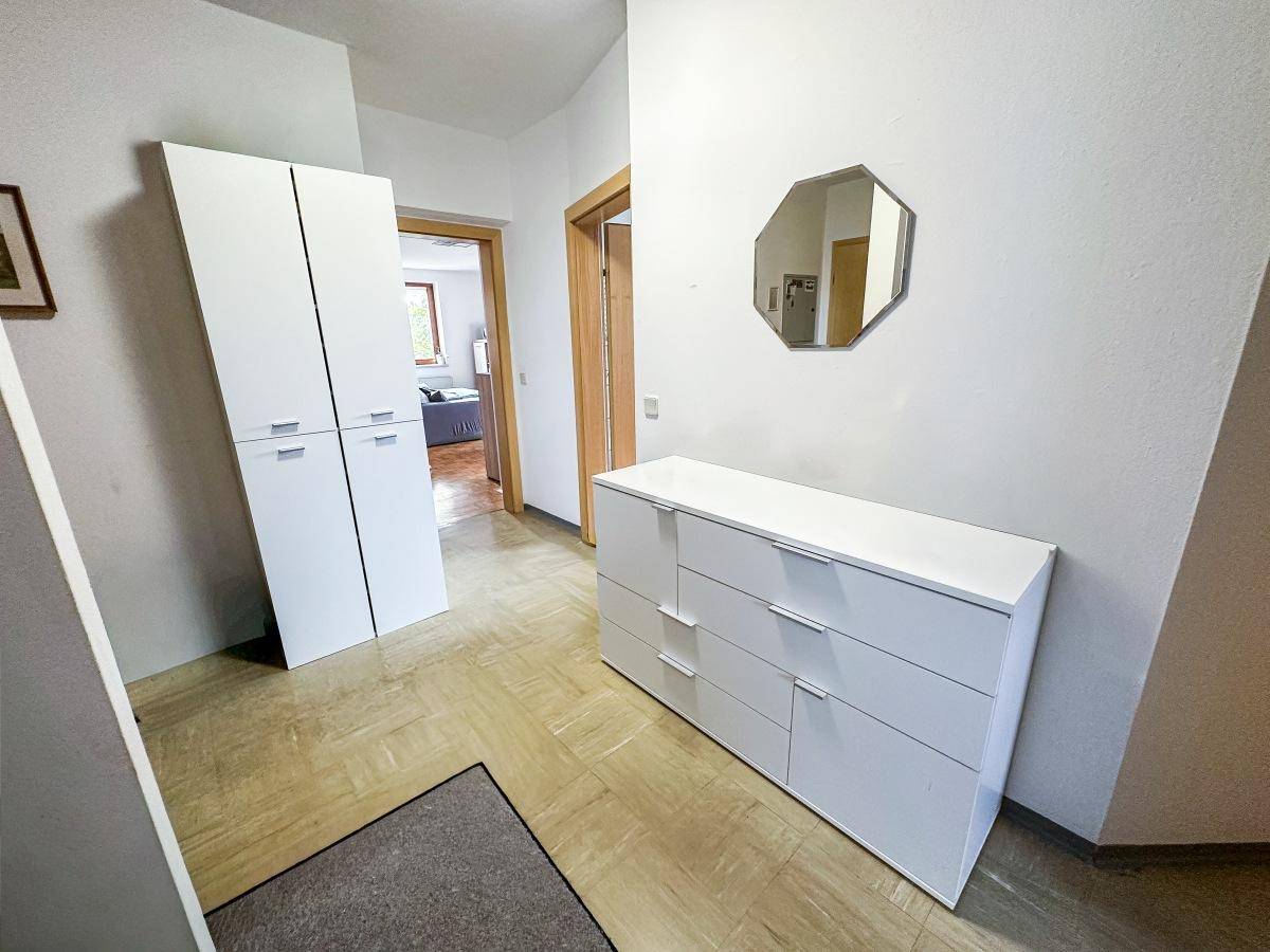 Geräumiger Flur mit weißer Kommode, Spiegelschrank und Zugang zu weiteren Zimmern.