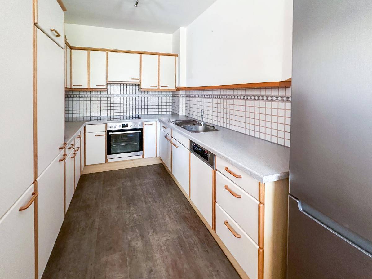 Funktionale Küche mit weißen Schränken, hellen Arbeitsplatten und integrierten Geräten.