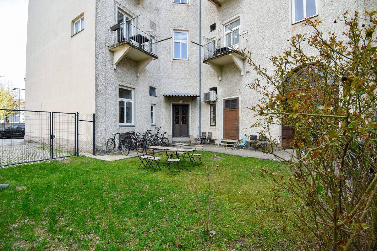 Kleiner begrünter Gartenbereich mit Sitzgelegenheiten und Blick auf die Gebäudefassade.