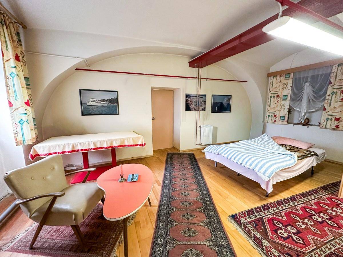 Schlafzimmer im Keller mit gewölbter Decke, Holzfußboden und Teppichen.