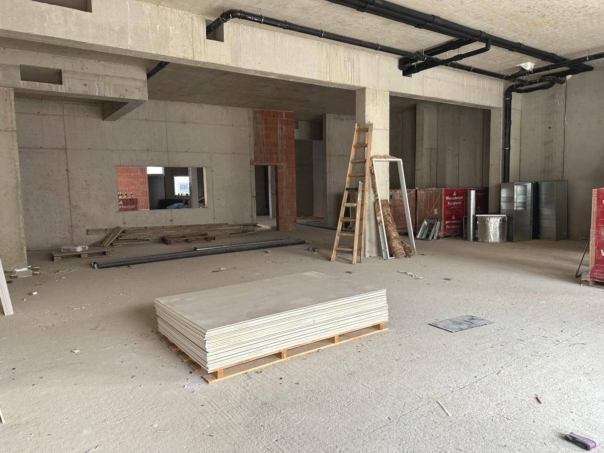 Geräumiger Rohbau mit Betonwänden, Leitern und Baustoffen, der auf den Innenausbau wartet.